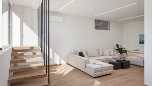 Una sala de estar moderna con una escalera, un conjunto de sofás y una mesa de centro.