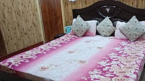 A bed with a floral bedspread, a wooden headboard, and decorative pillows. - River View Bamboo Resort (Lansdowne)