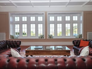 A room with a large window, a leather sofa, and a coffee table. - Alston Hall (Plymouth)