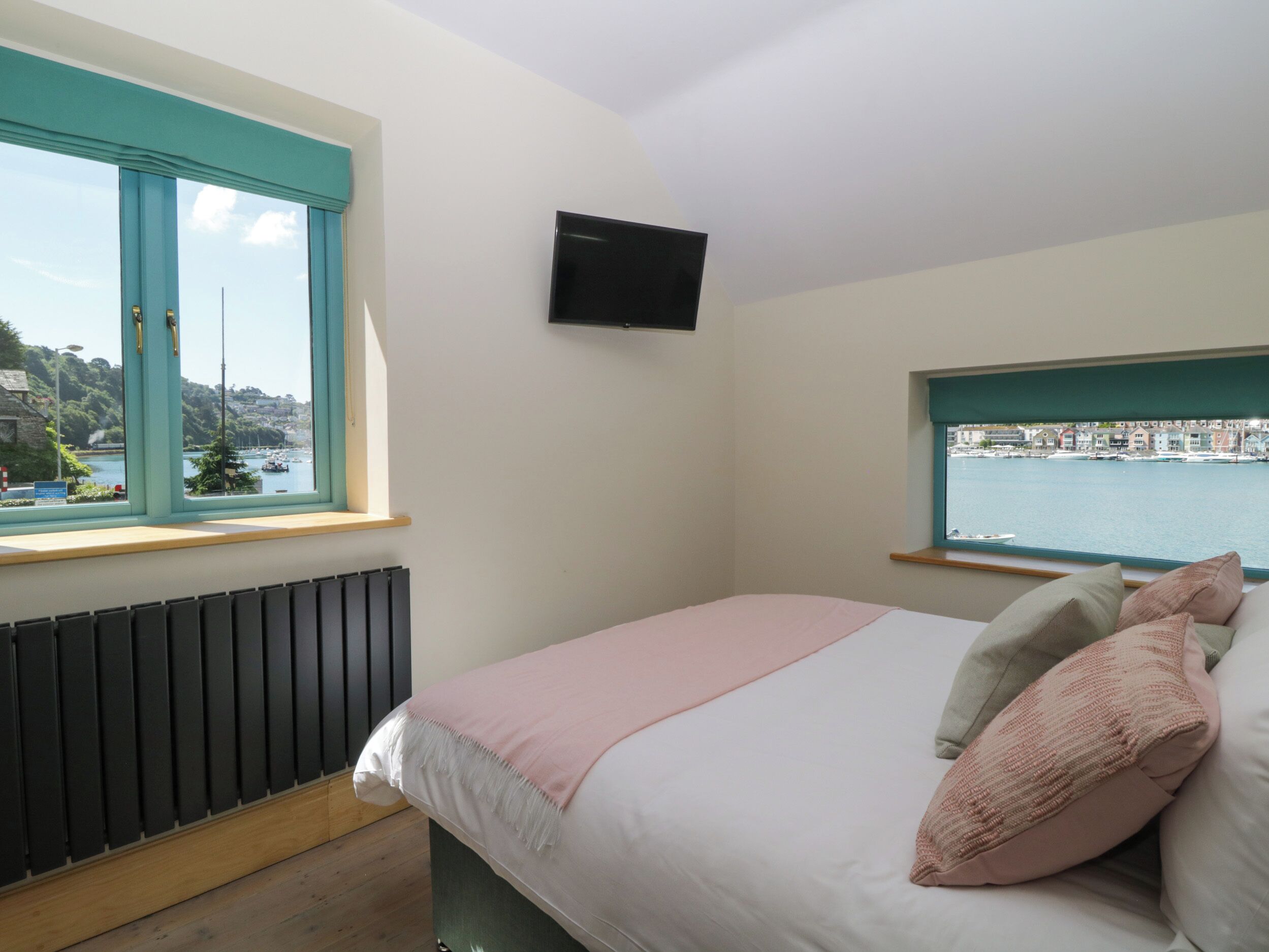 Una camera da letto con un letto, una TV a muro e una finestra con vista sul porto.
