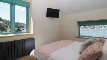 Una camera da letto con un letto, una TV a muro e una finestra con vista sul porto.
