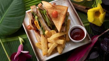 A plate with a sandwich, fries, and a small bowl of ketchup.