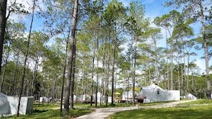 A campground with white cabins, a paved path, and a grassy area. - Romdoul Kirirom Resort by EHM (Kampong Seila)