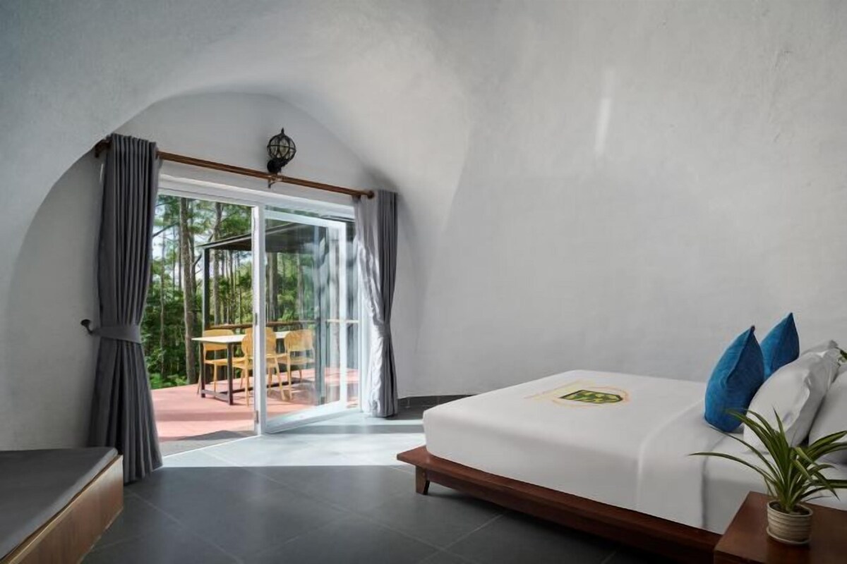 Un dormitorio con cama, ventana con cortinas y vista a un espacio exterior.