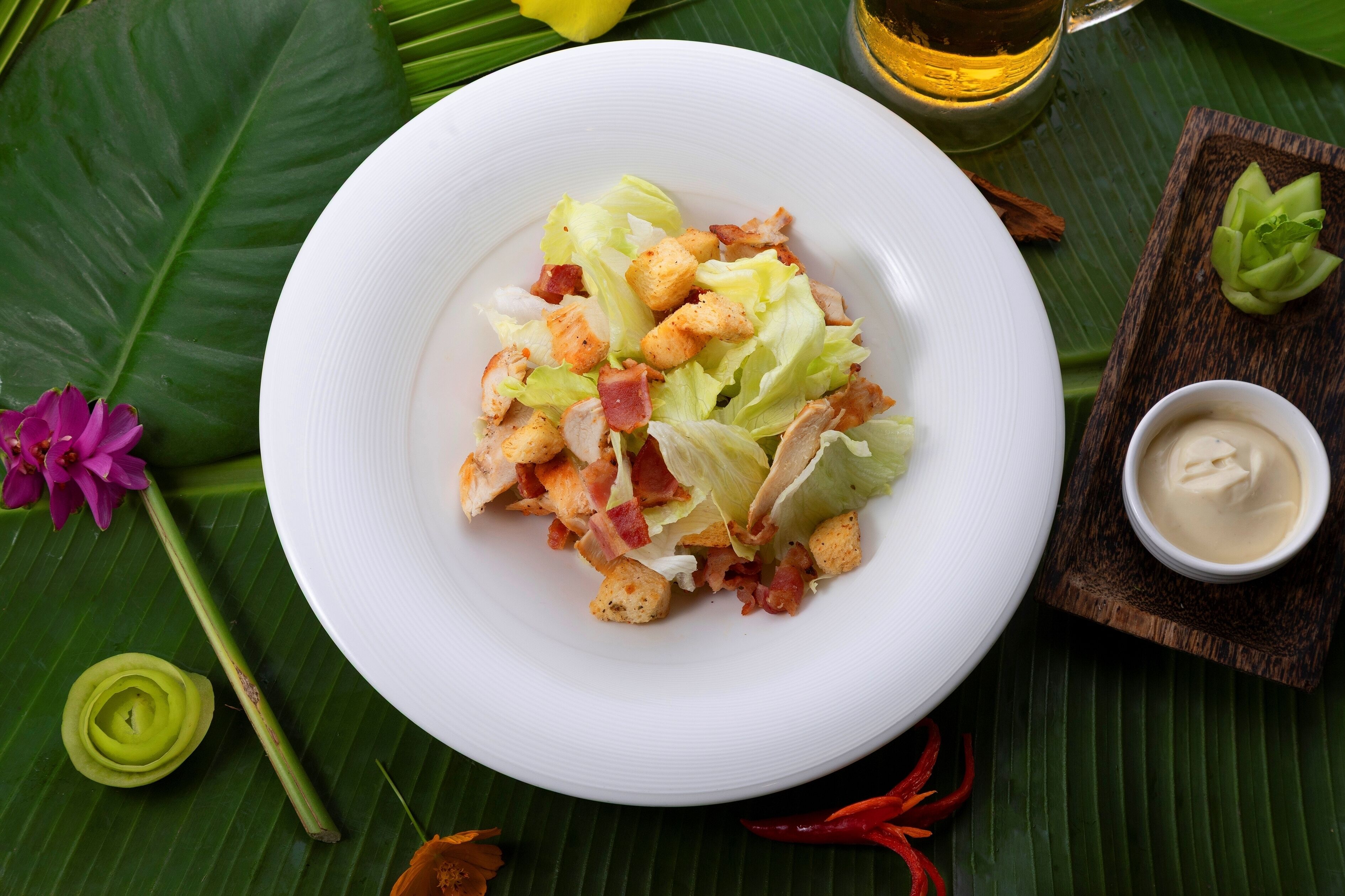 A white plate with a salad on a green leaf.