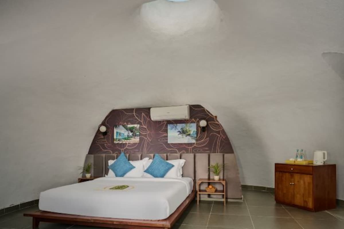Un dormitorio con una cama, una mesita de noche, un armario pequeño y un aire acondicionado instalado en la pared.