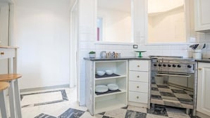 Una cocina con armarios blancos, una estufa y piso a cuadros.