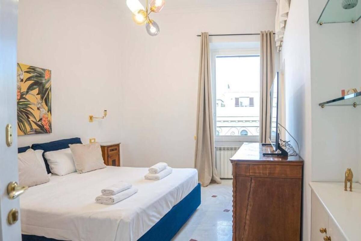 Une chambre d’hôtel avec un lit, un bureau, un miroir et une fenêtre donnant sur des immeubles.