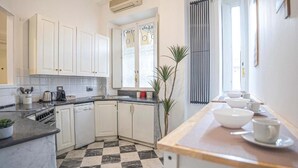 Una cocina moderna con armarios blancos, piso a cuadros y encimera de madera con utensilios de cocina.