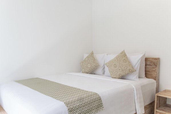 A neatly made bed with a patterned throw, white bedding, and two decorative pillows.