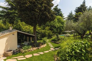 A garden with a stone pathway, a pool, and a building with a covered patio.