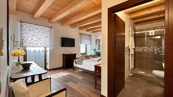 Une pièce avec un plafond en bois, un lit, une télévision, une table avec une lampe et un espace douche.