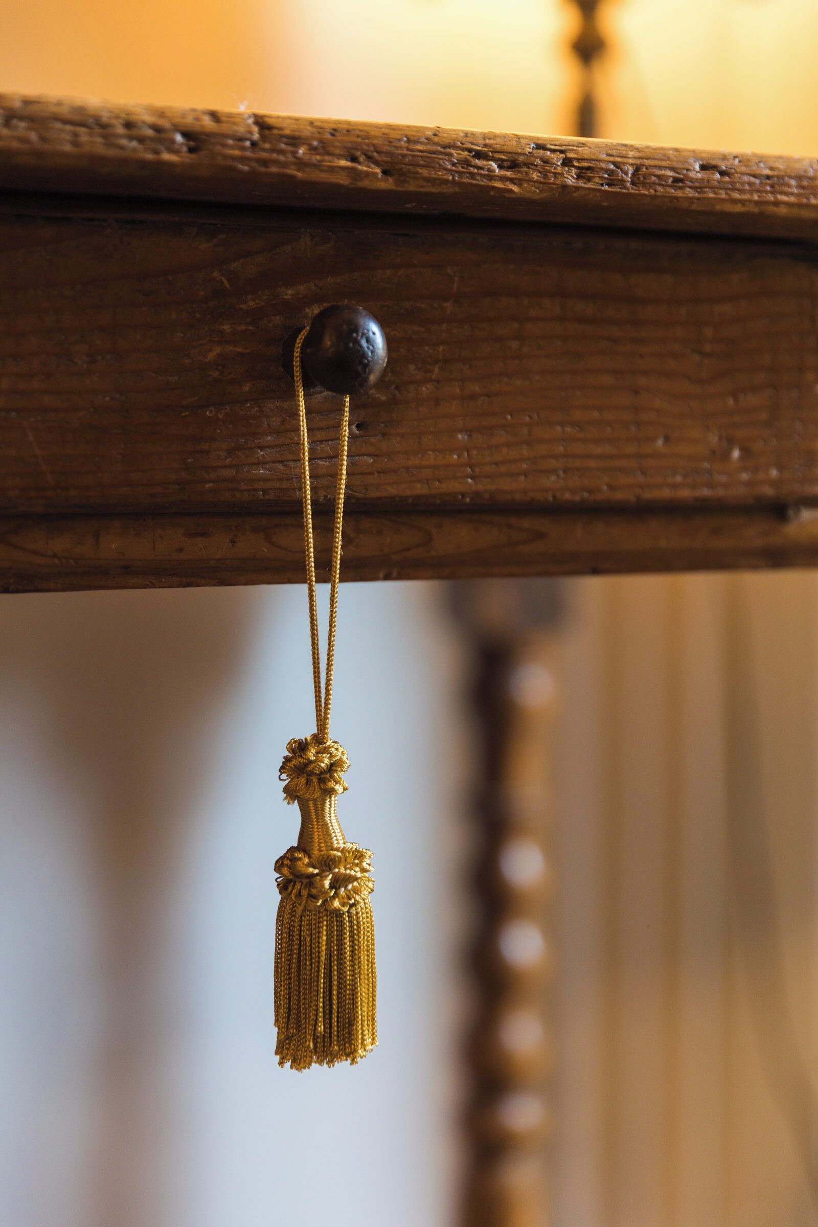 A wooden surface with a spherical object and a tassel hanging from it.