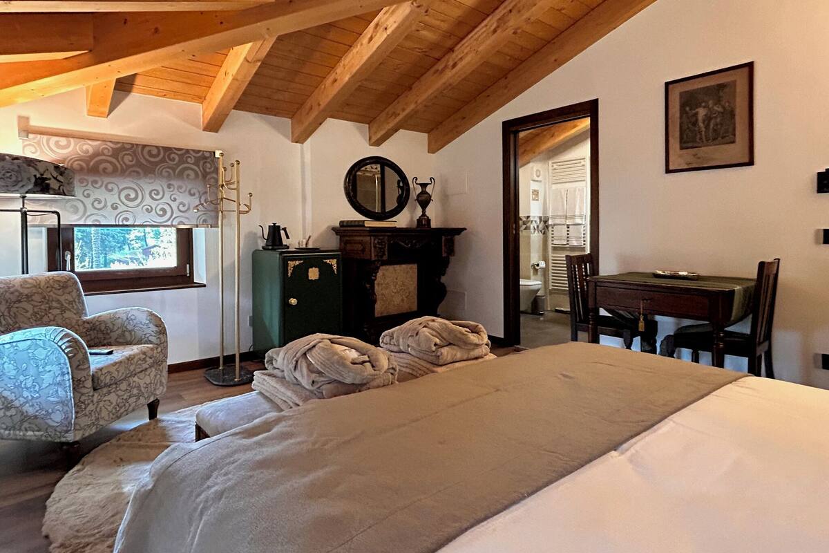 A room with a bed, a chair, a desk, a mirror, and a window.