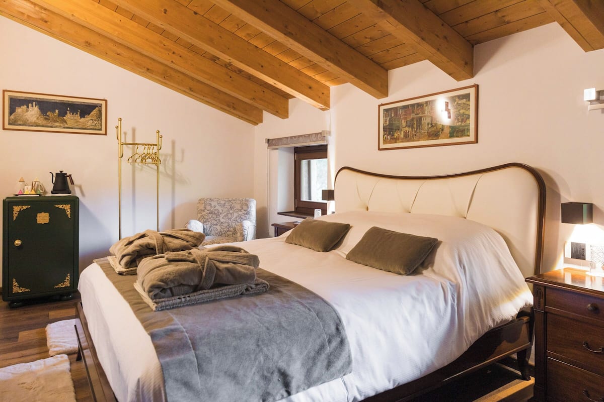 A bedroom with a bed, a dresser, a chair, and a coat rack.