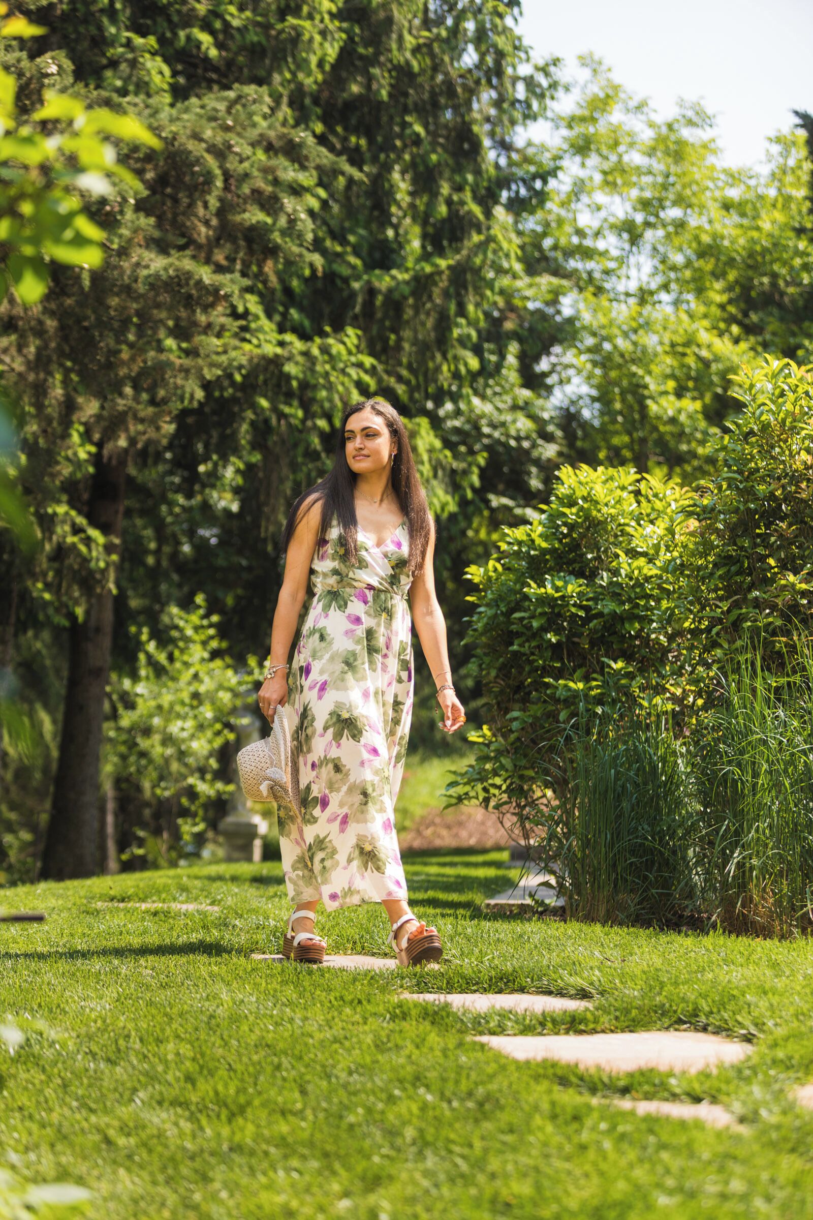 A woman walking on a grassy path in a park-like setting.