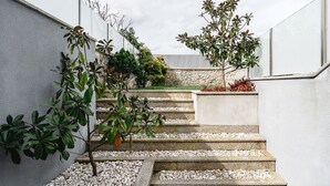 A set of stone steps leading up to a garden area with a variety of plants and a small tree.