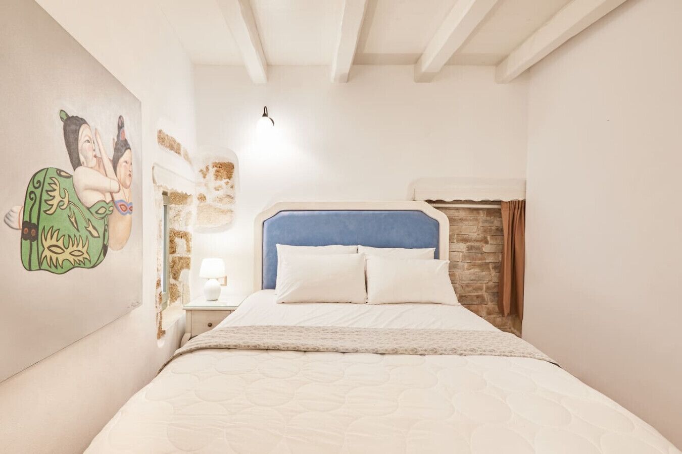 Une chambre à coucher comprenant un lit, une table de chevet, une lampe fixée au mur et un élément décoratif mural.