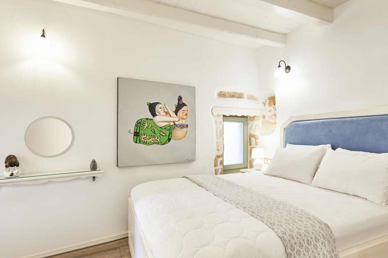 Une chambre à coucher avec un grand lit, une table de chevet, un miroir fixé au mur et un tableau.