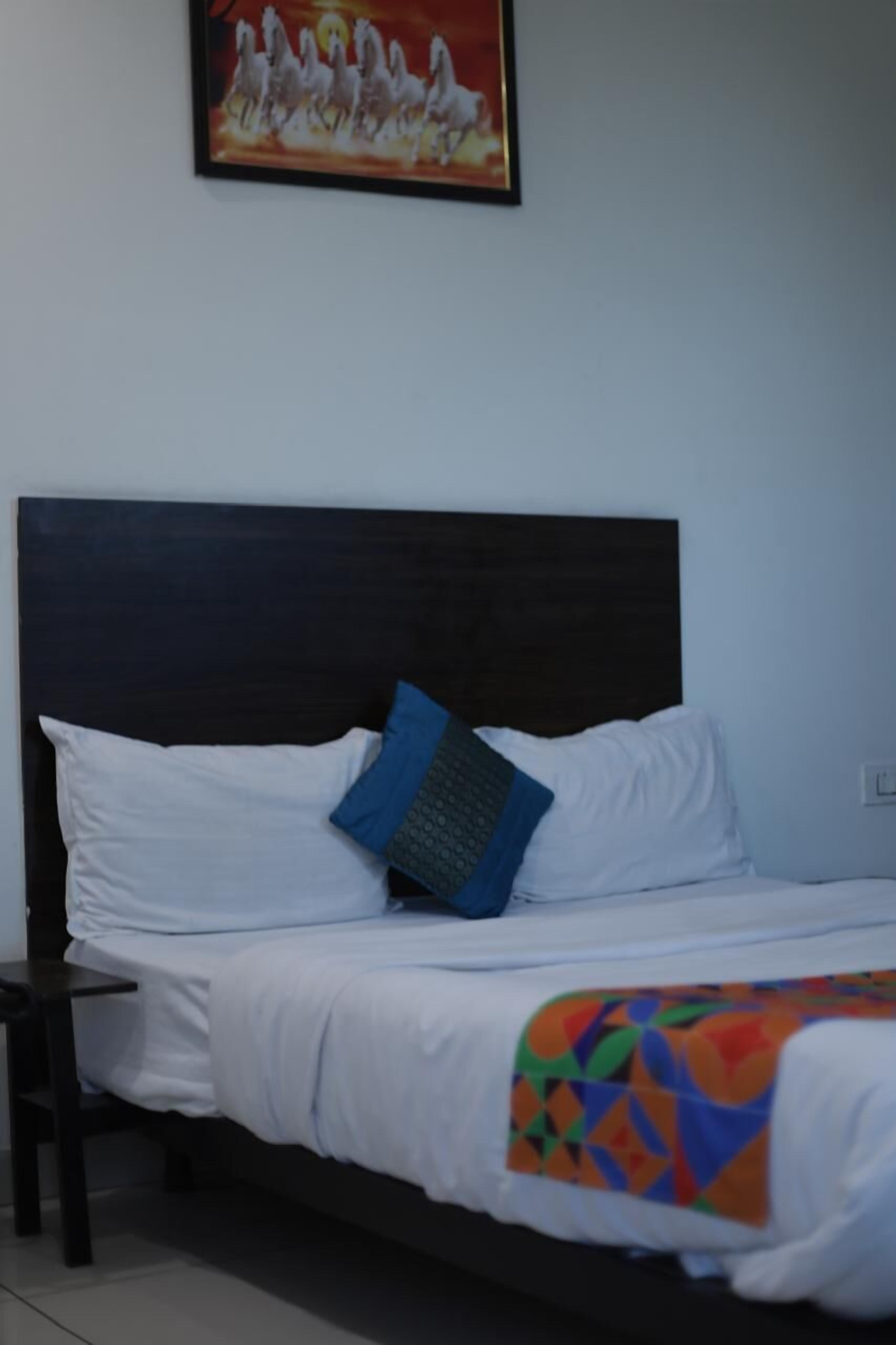 Una cama bien tendida con sábanas blancas y una manta geométrica de colores.