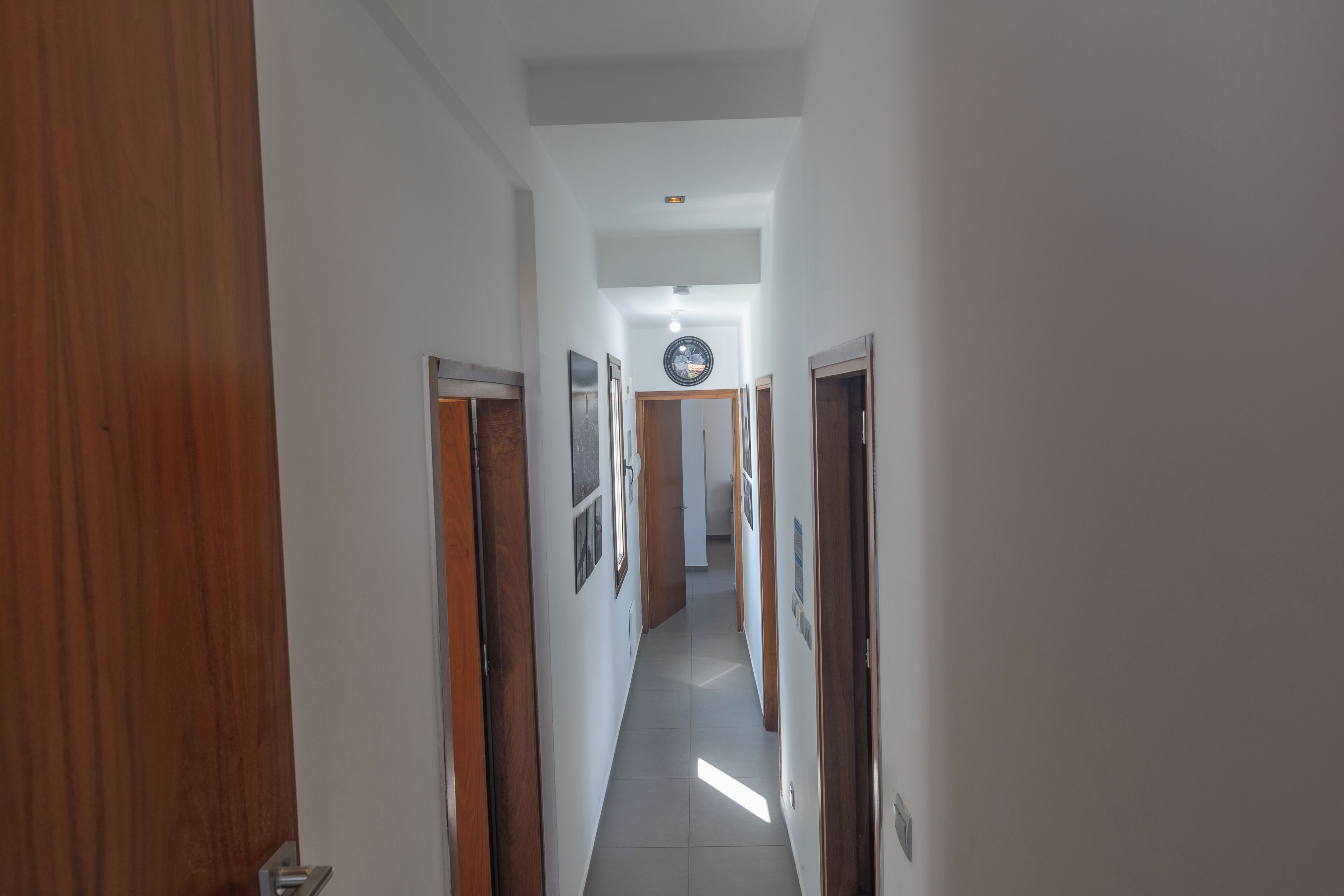 A narrow hallway with wooden doors on either side and a tiled floor.