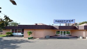 Ένα κτίριο με την επιγραφή «Τουριστικό Συγκρότημα Σάντπαιπερ», με μια ευδιάκριτη είσοδο και έναν χώρο στάθμευσης μπροστά του.