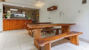 A dining area with wooden benches and a kitchen in the background.