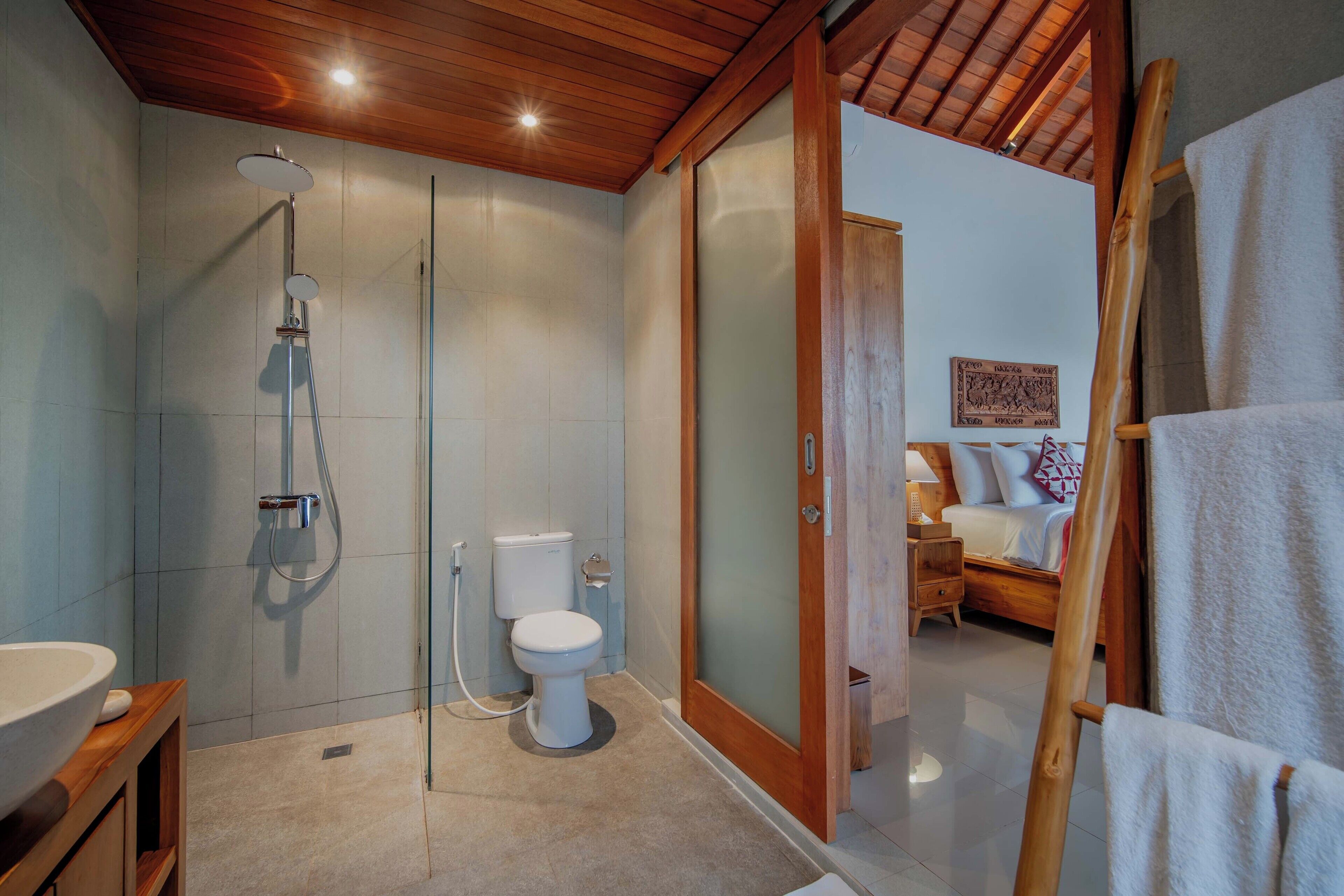 Un baño moderno con ducha de vidrio, inodoro y techo de madera.