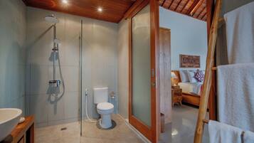 Un baño moderno con ducha de vidrio, inodoro y techo de madera.