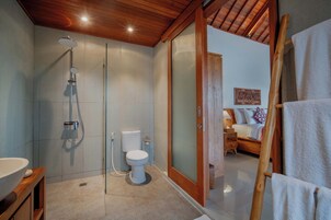 Un baño moderno con ducha de vidrio, inodoro y techo de madera.