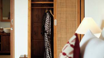 A wooden wardrobe with a hanging garment, a wicker basket, and a bedside lamp.