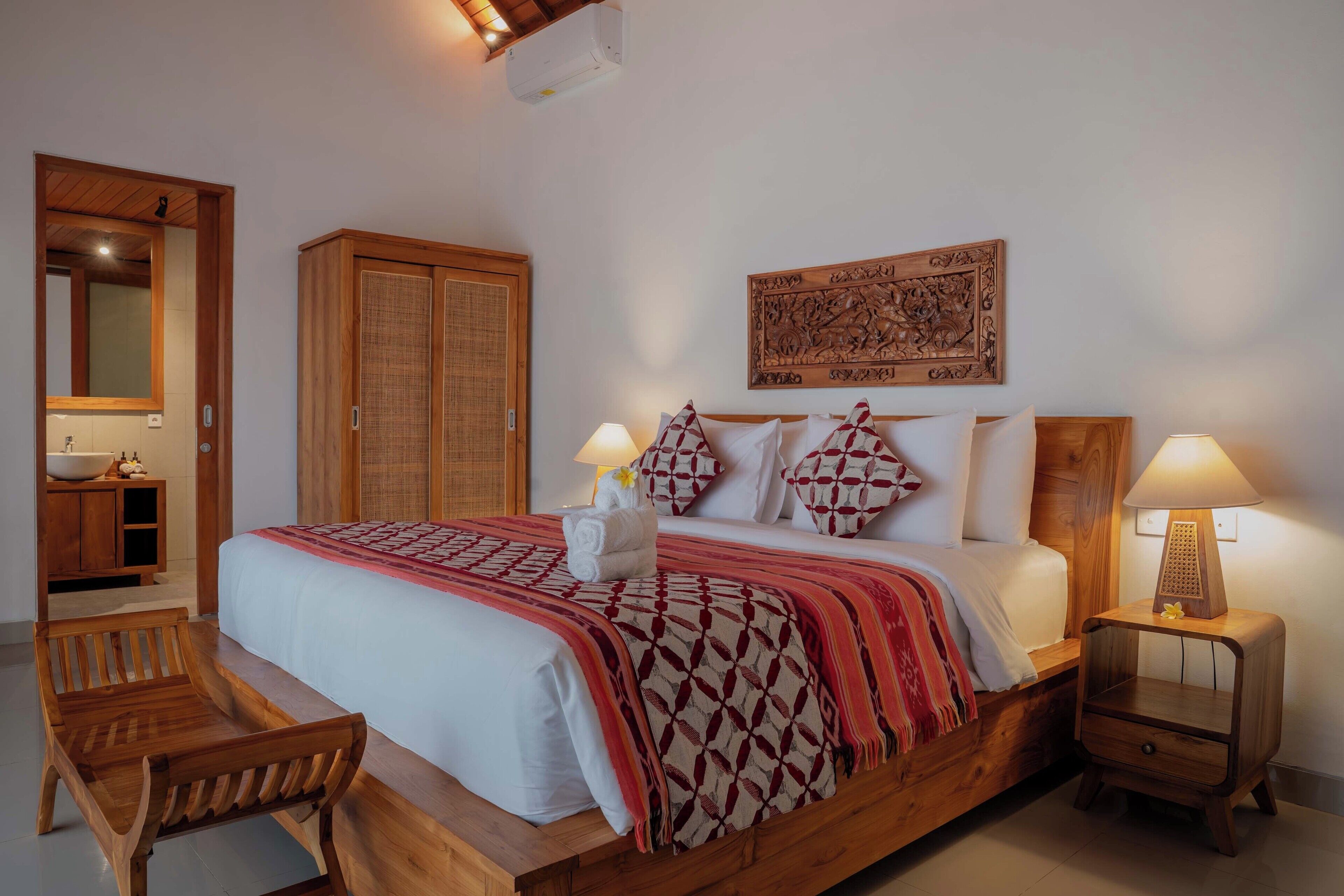 A wooden bed with a patterned blanket, two bedside lamps, and a wooden nightstand.