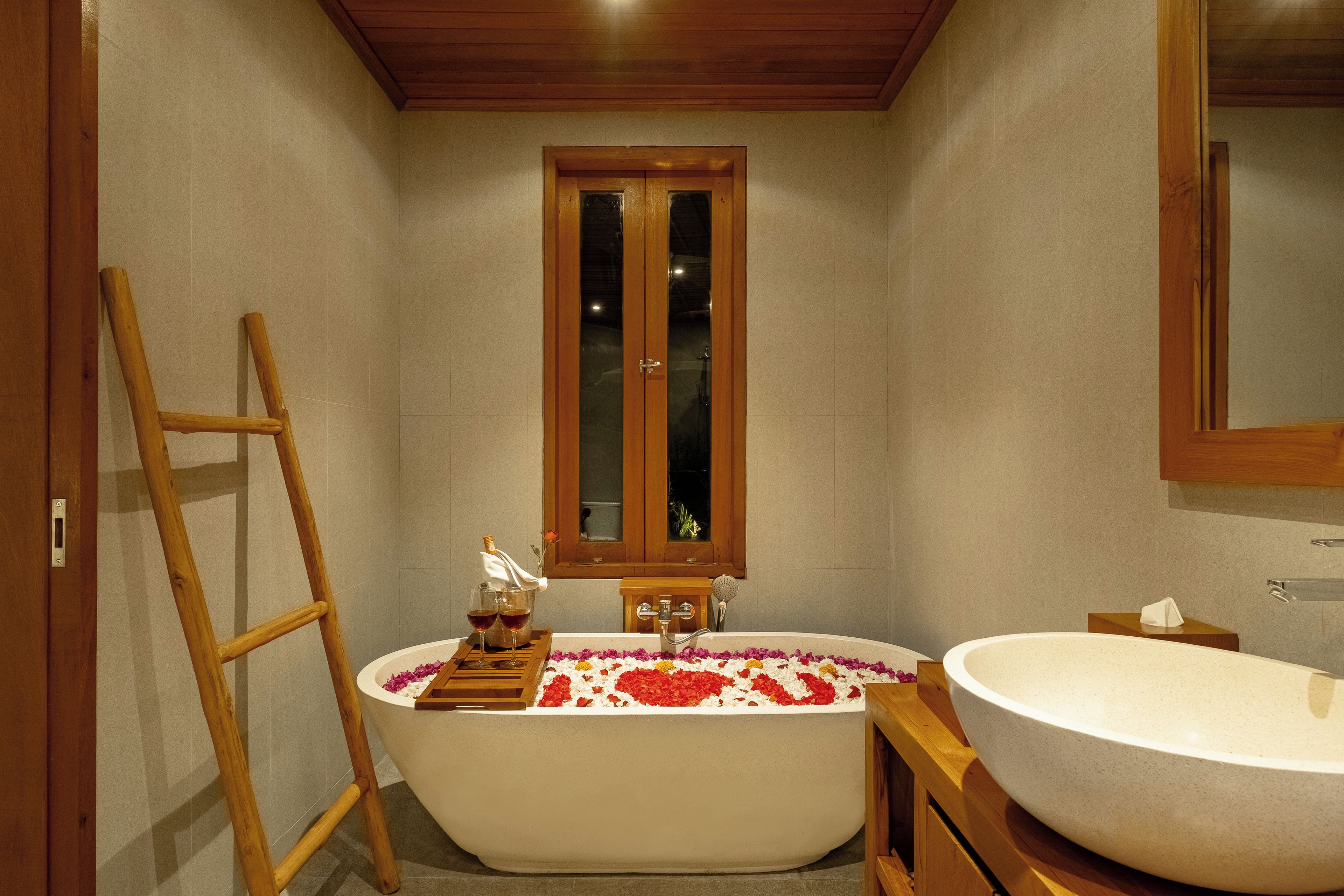 A bathroom with a freestanding bathtub, a wooden ladder, a wooden cabinet, and a large mirror.