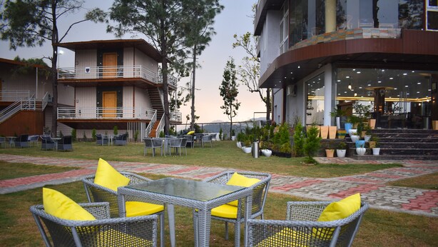 A hotel courtyard with outdoor seating, a staircase, and a building with a balcony. - PRAKRTI-THE NATURE (Lansdowne)