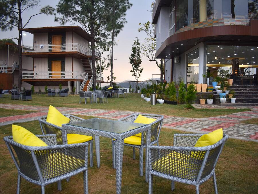 A hotel courtyard with outdoor seating, a staircase, and a building with a balcony.