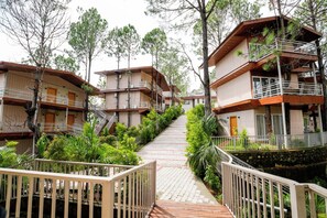 Un edificio de varios pisos con balcones, rodeado de árboles y un sendero pavimentado.