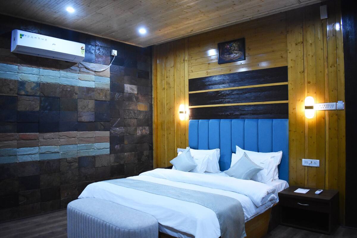 Une chambre avec un mur en pierre, un lambris en bois, une tête de lit bleue et des lampes de chevet.