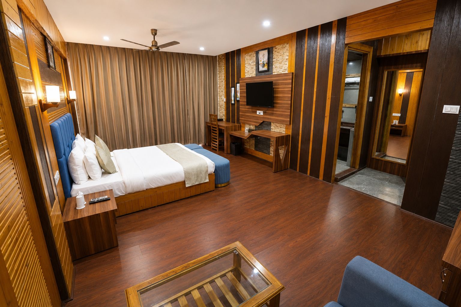 A hotel room with a bed, a desk, a TV, and a ceiling fan.