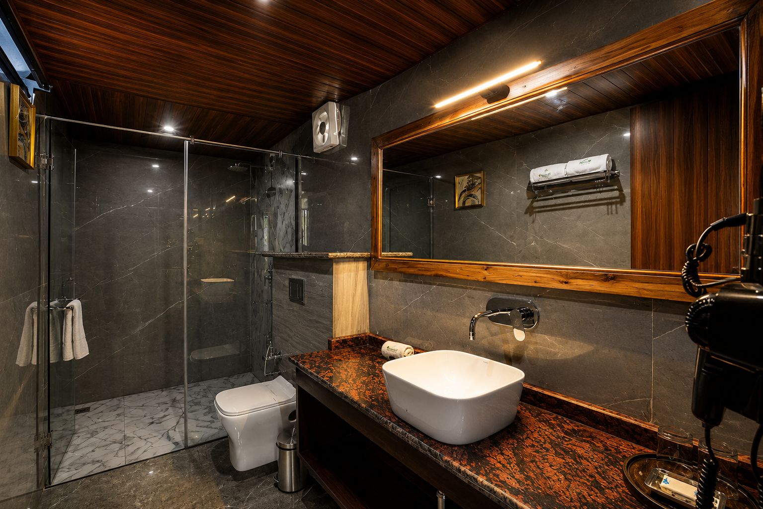 Un bagno moderno con cabina doccia in vetro, lavandino bianco e mobile vanitario in legno.
