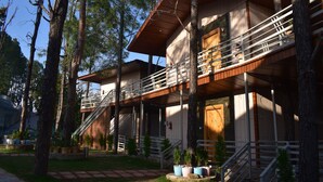 A multi-story wooden building with external staircases and balconies, surrounded by trees. - PRAKRTI-THE NATURE (Lansdowne)