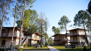 A resort with multiple-story buildings, outdoor seating areas, and a central pathway. - PRAKRTI-THE NATURE (Lansdowne)