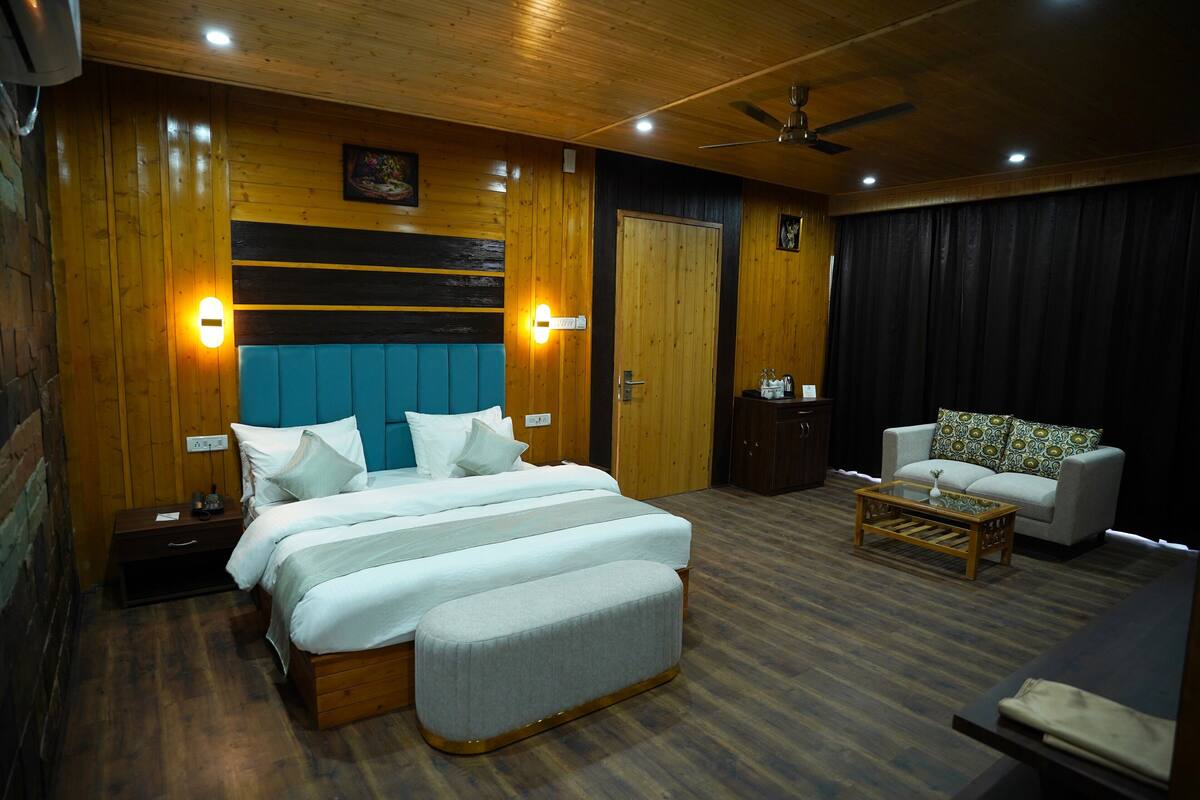 Une chambre d’hôtel avec un grand lit, un canapé, une table basse et un ventilateur de plafond.