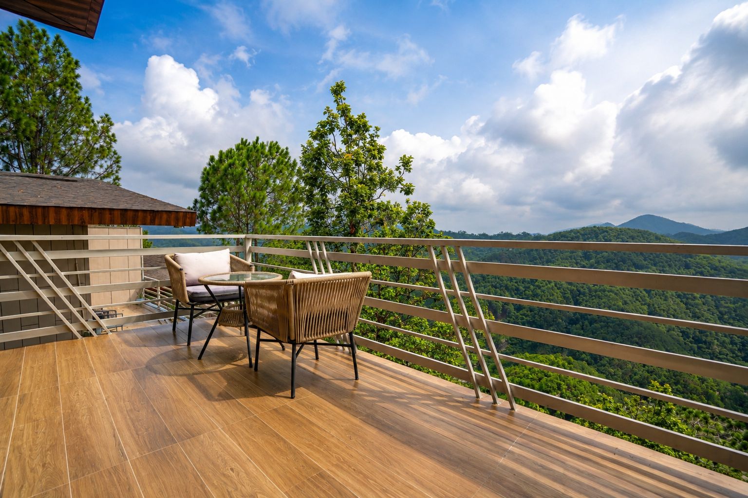 A wooden deck with a table and chairs, overlooking a lush green landscape with mountains in the distance.