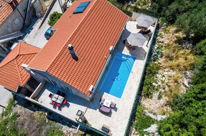 Piscina no terraço com cobertura de telhas vermelhas, área de estar ao ar livre e vista para a paisagem ao redor.