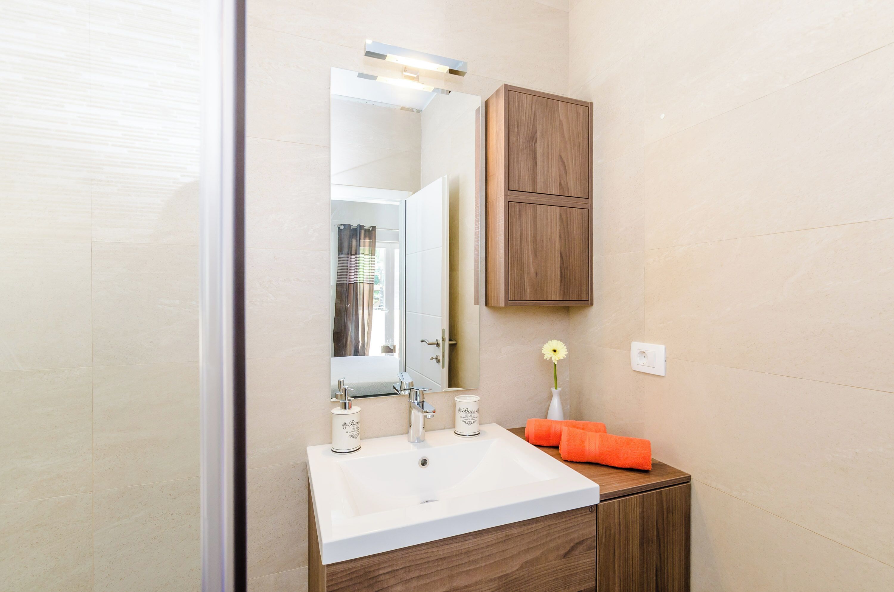 A bathroom with a white sink, wooden cabinet, and a mirror.