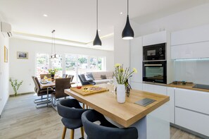 Een moderne keuken met witte kastjes, een houten eiland en zwarte hanglampen.