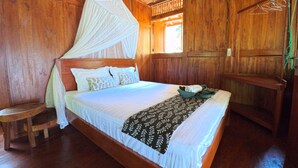 A wooden room with a bed, a bench, and a window.