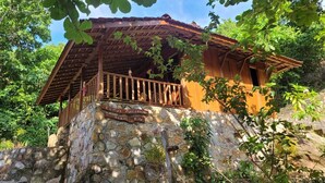 A stone building with a wooden balcony and a sign that reads "Rumah Manisfesti Alam Kota".