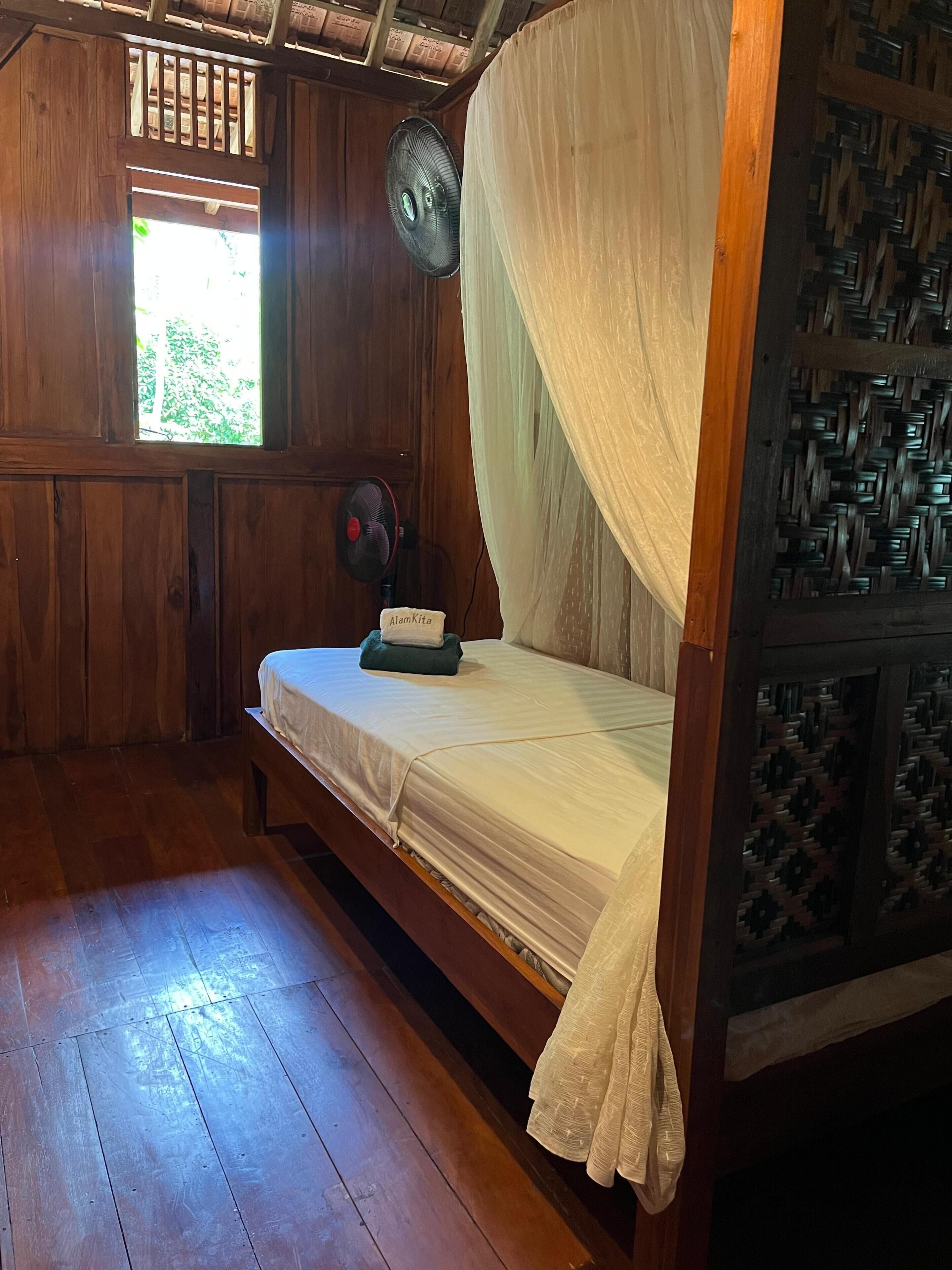 Una habitación de madera con una cama, un ventilador y una ventana.