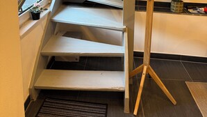 Eine Treppe mit Holzgeländer und einem Fenster mit Jalousien.